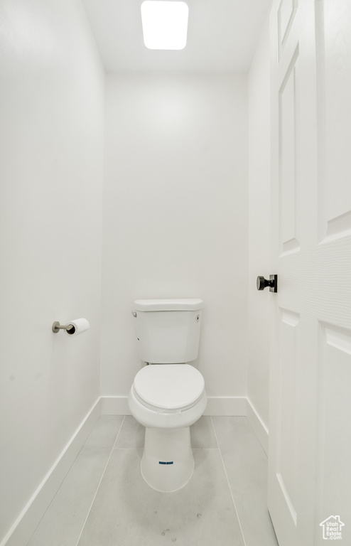 Bathroom with baseboards, tile patterned floors, and toilet