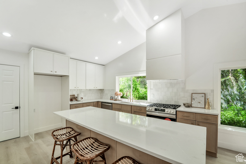 Kitchen featuring a sink, a breakfast bar, stainless steel appliances, and light wood-style flooring