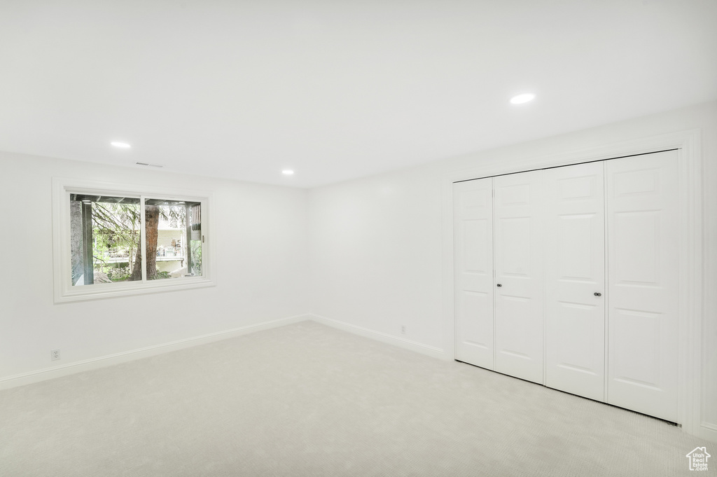 Unfurnished bedroom featuring light colored carpet, recessed lighting, baseboards, and a closet