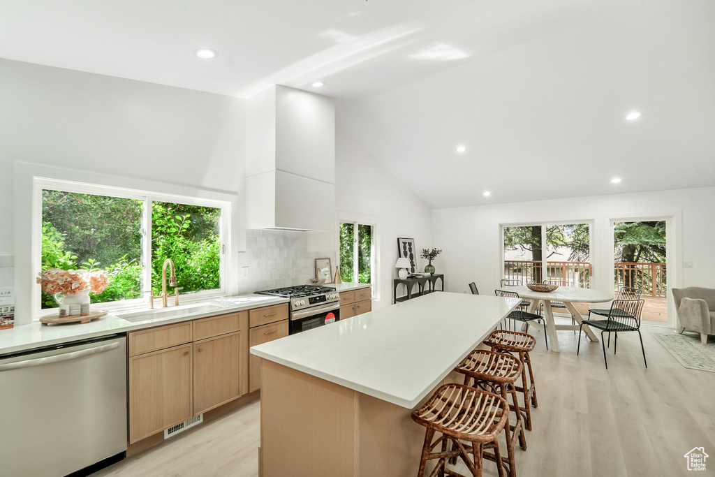 Kitchen with a kitchen bar, visible vents, light wood-type flooring, a sink, and stainless steel appliances