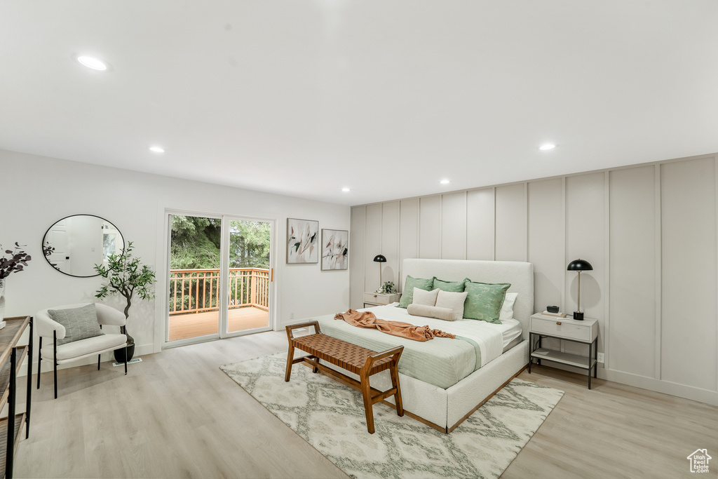 Bedroom with access to outside, light wood-style floors, recessed lighting, and a decorative wall