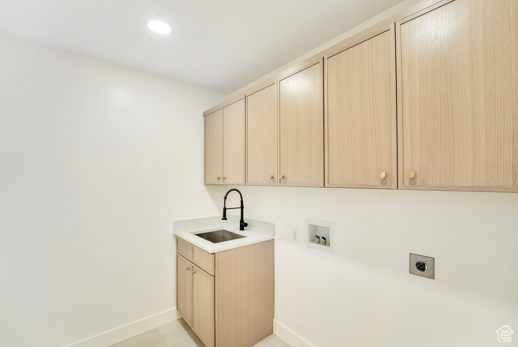 Laundry room featuring electric dryer hookup, cabinet space, a sink, baseboards, and hookup for a washing machine