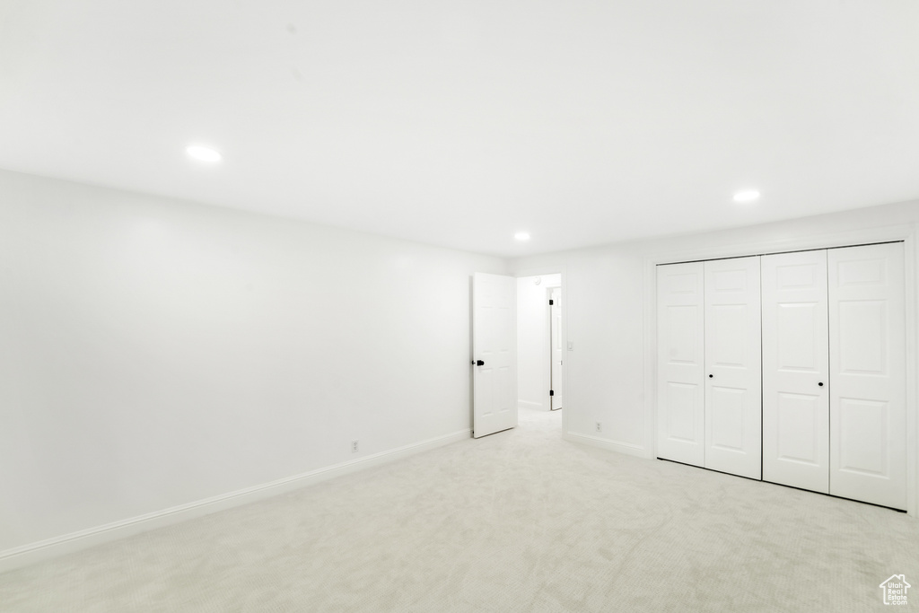 Unfurnished bedroom featuring recessed lighting, light colored carpet, and a closet