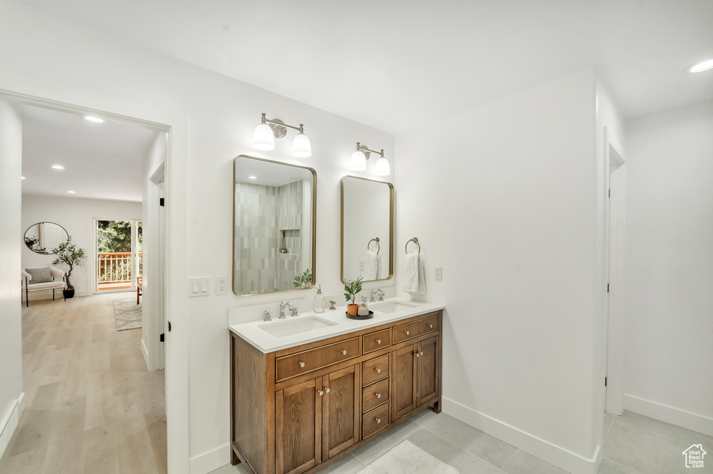 Full bathroom with double vanity, a sink, baseboards, and recessed lighting