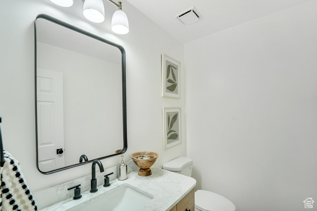 Bathroom featuring visible vents, toilet, and vanity
