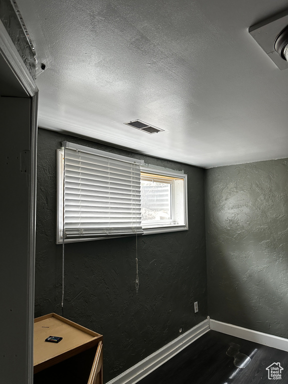Spare room featuring visible vents, a textured wall, wood finished floors, baseboards, and a textured ceiling