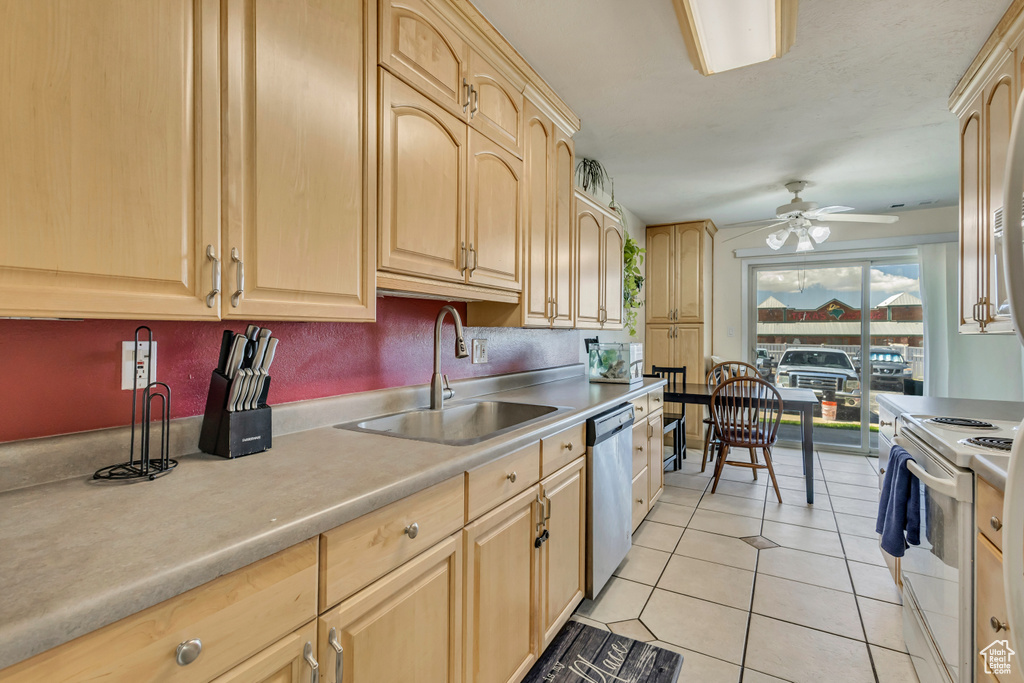 Kitchen with stainless steel dishwasher, a sink, light countertops, light brown cabinets, and white electric range oven