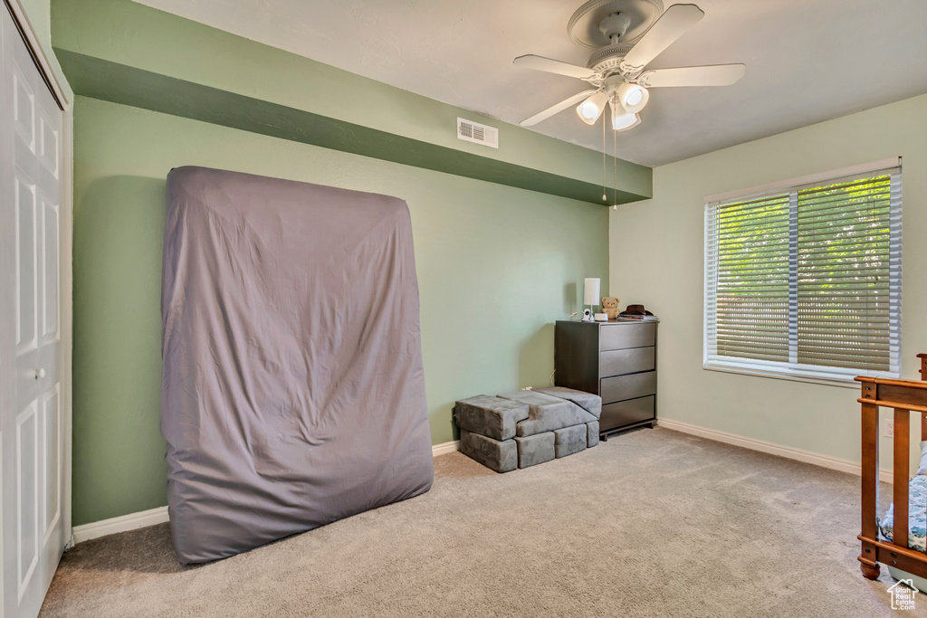 Carpeted bedroom with visible vents, baseboards, ceiling fan, and a closet