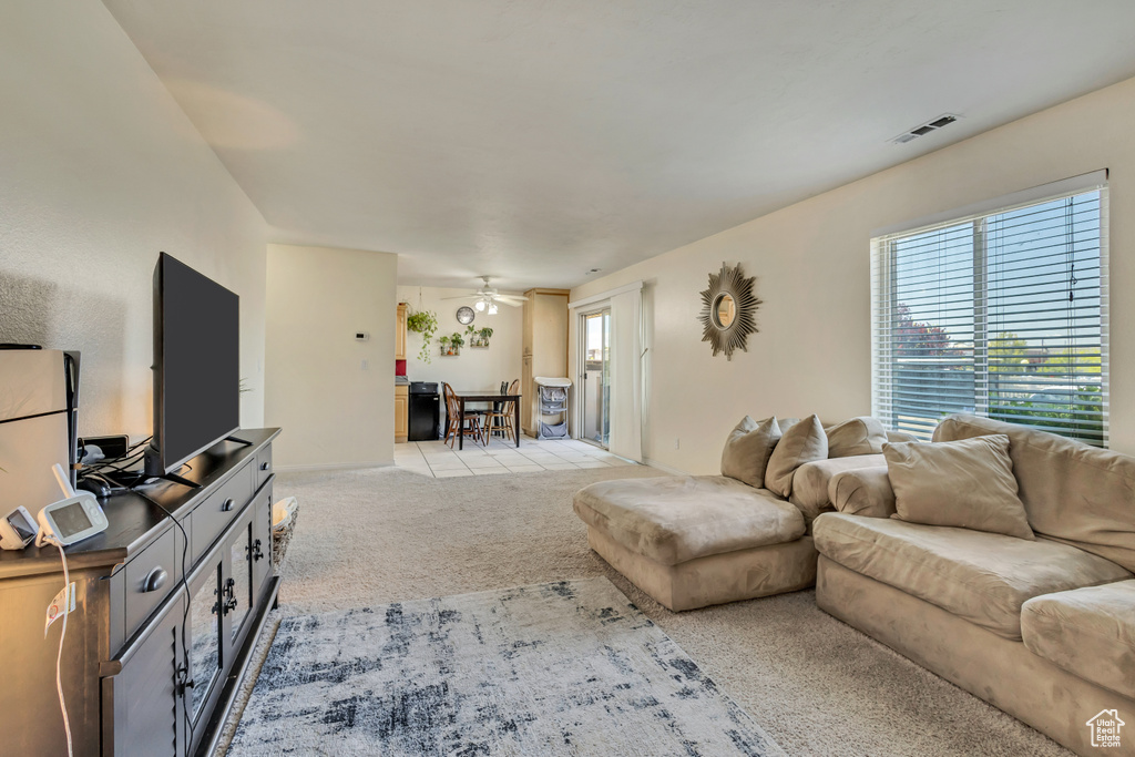 Living room with light colored carpet, a ceiling fan, and visible vents