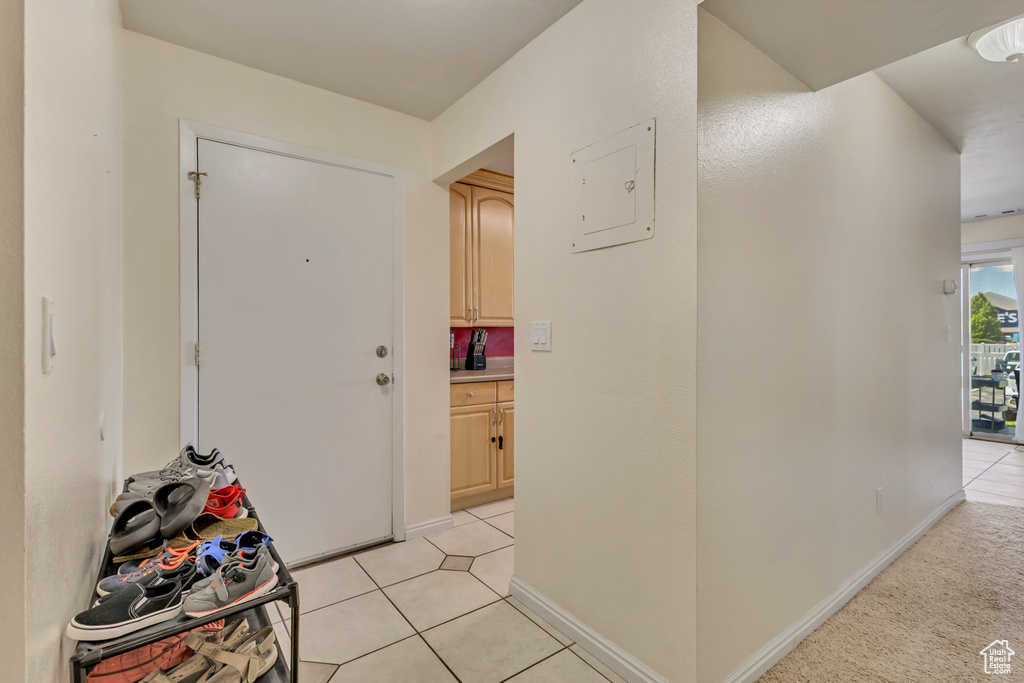 Corridor featuring light tile patterned flooring, baseboards, and electric panel