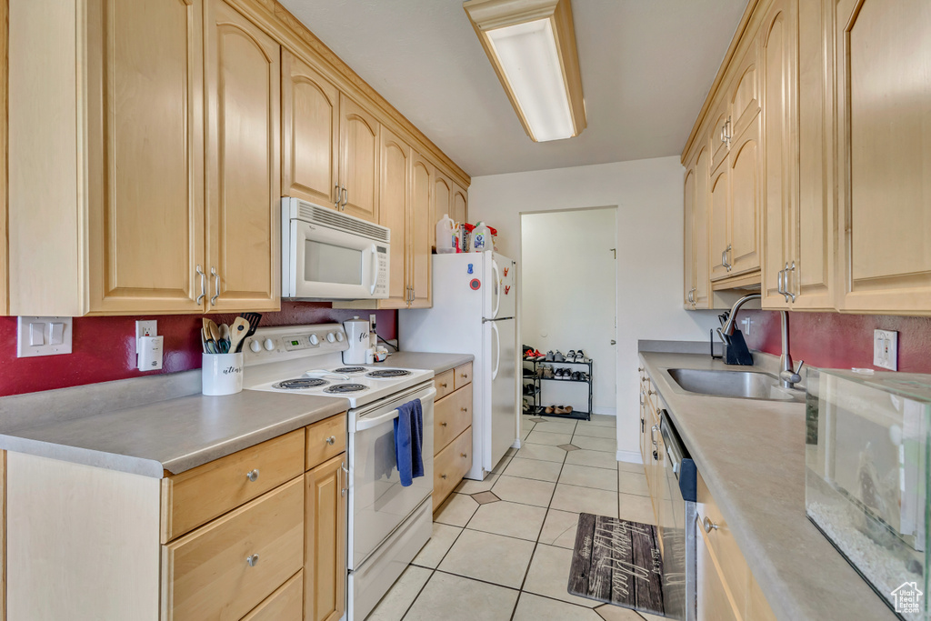 Kitchen with a sink, light brown cabinetry, light tile patterned flooring, and white appliances