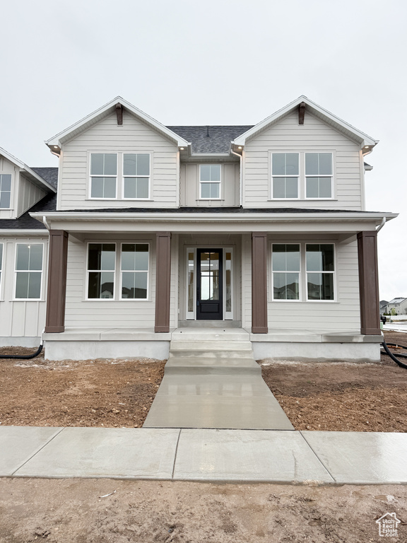 View of front of property with roof with shingles and covered porch