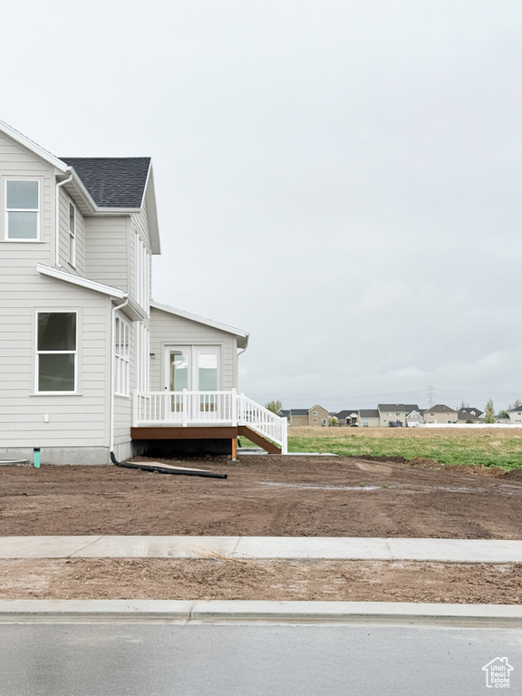 Exterior space with roof with shingles and a deck