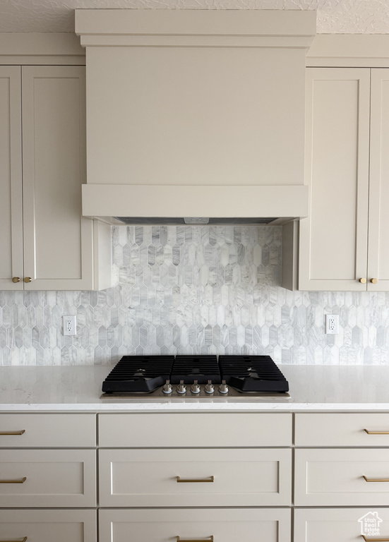 Kitchen featuring premium range hood, light countertops, tasteful backsplash, and stainless steel gas stovetop