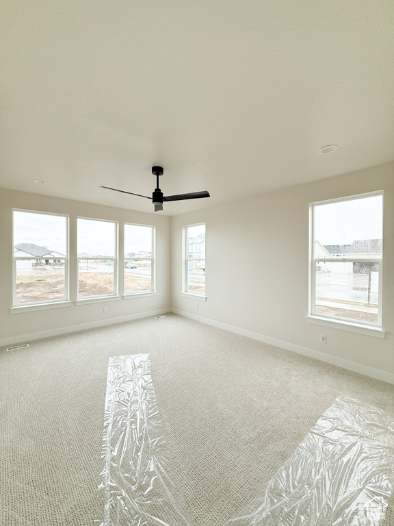 Empty room with baseboards, a ceiling fan, visible vents, and carpet