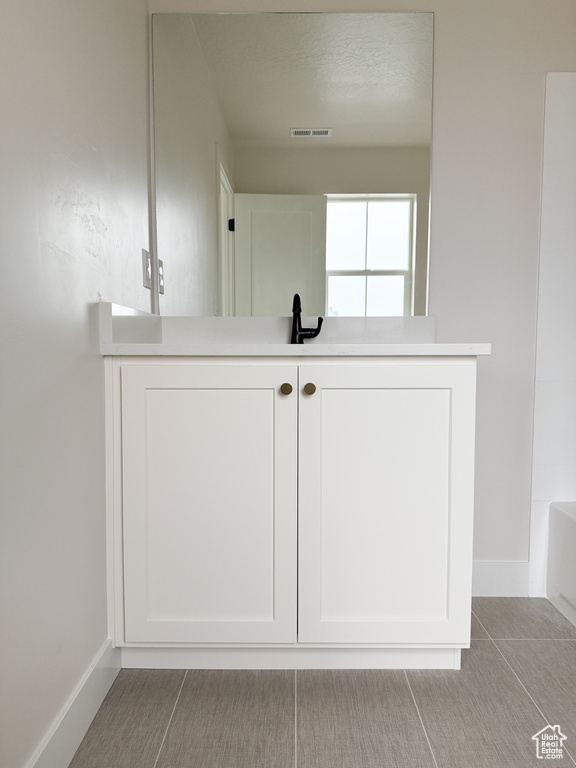Full bath with a bath, baseboards, visible vents, and vanity