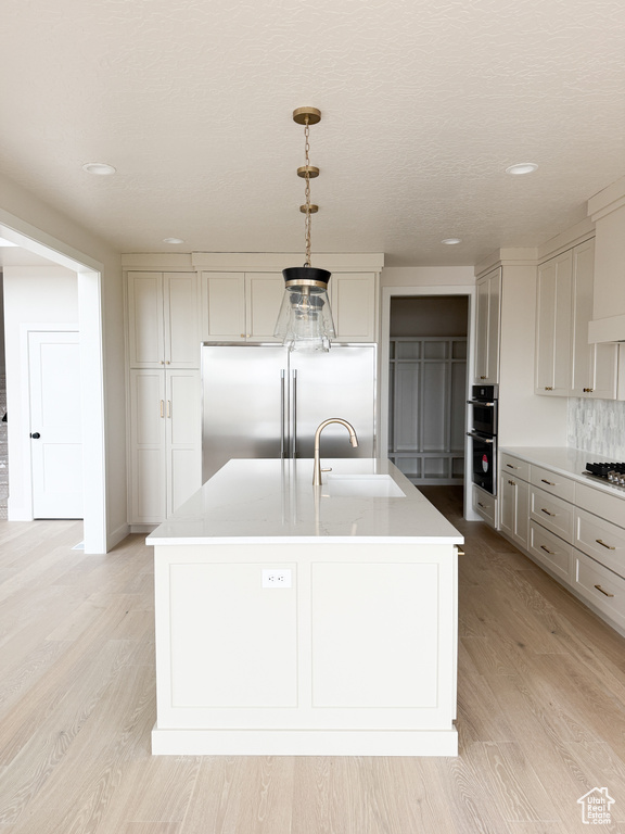 Kitchen with light countertops, a sink, recessed lighting, and appliances with stainless steel finishes
