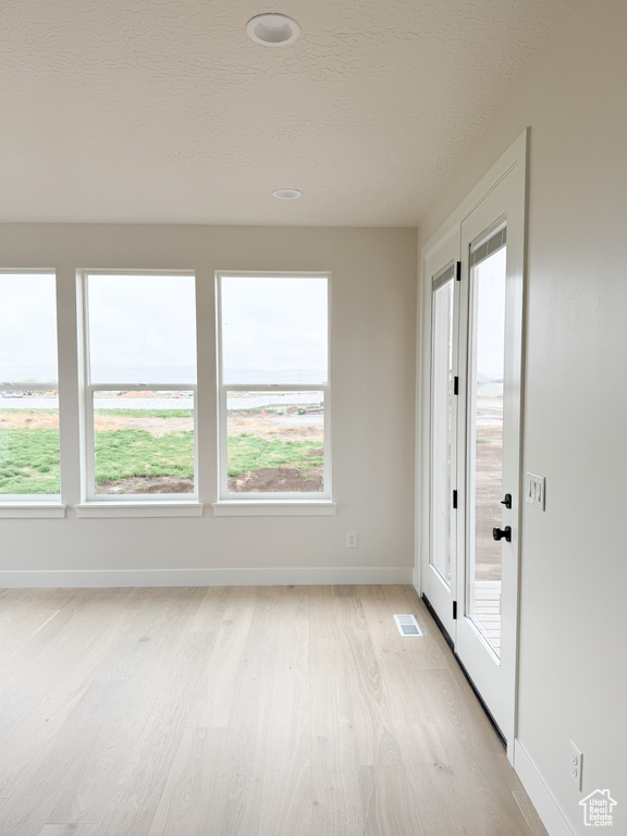 Unfurnished room with a wealth of natural light, baseboards, visible vents, and light wood-style flooring
