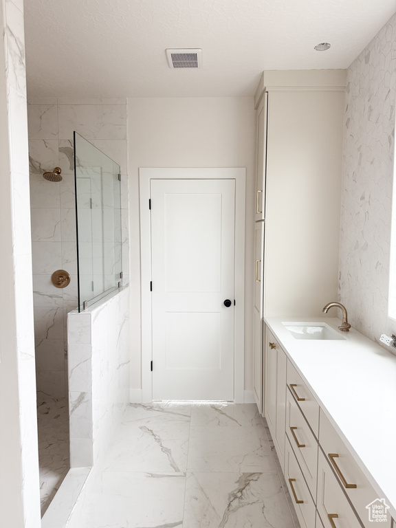Bathroom featuring visible vents, marble finish floor, vanity, and a marble finish shower