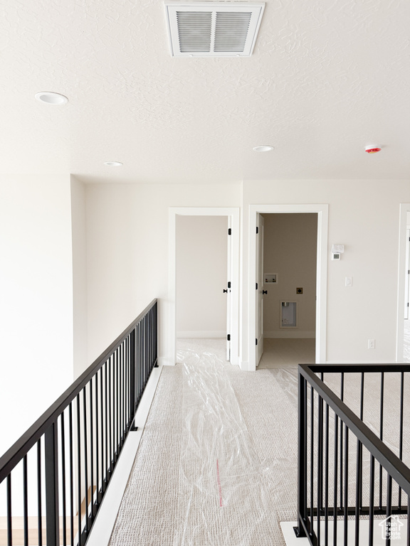 Hall with recessed lighting, visible vents, an upstairs landing, a textured ceiling, and light colored carpet