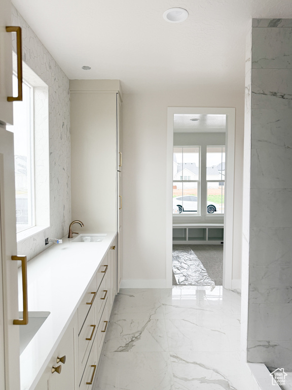 Bathroom with baseboards, marble finish floor, a sink, and double vanity