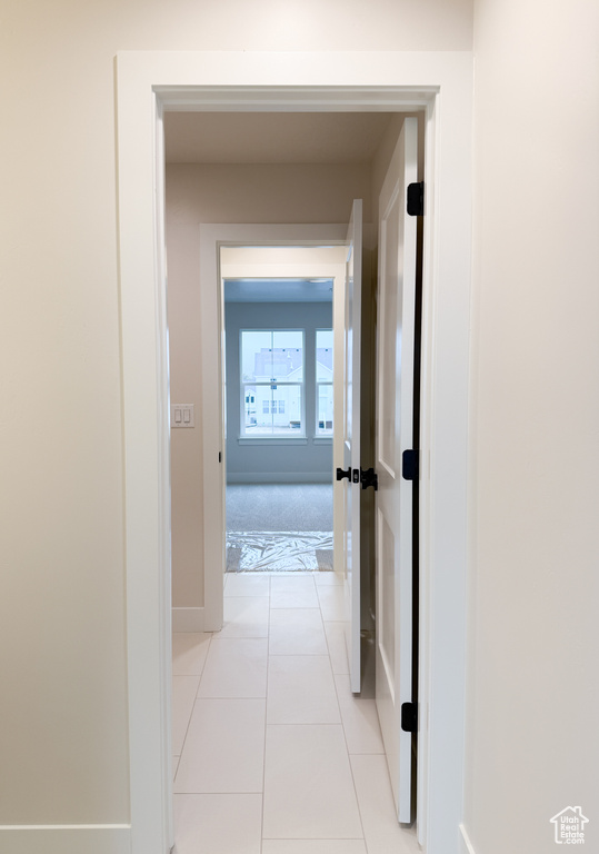 Hallway with baseboards and light tile patterned floors
