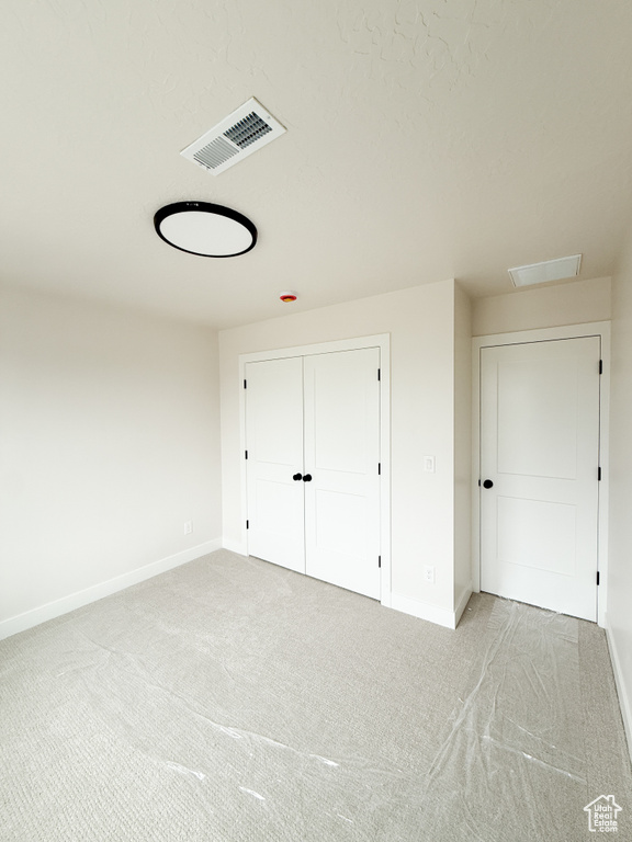 Unfurnished bedroom featuring baseboards, a closet, visible vents, and carpet