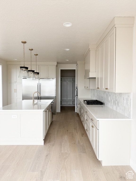 Kitchen with white cabinets, light countertops, a sink, and light wood-style flooring