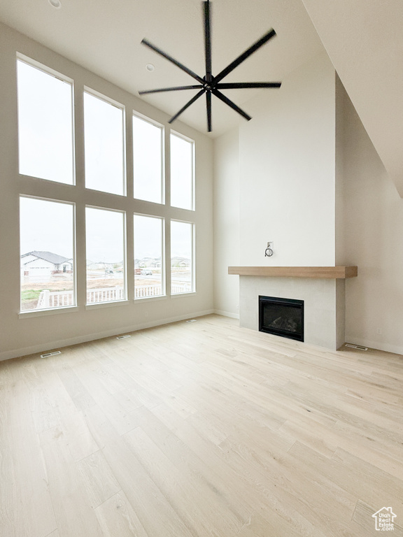 Unfurnished living room with baseboards, wood finished floors, a fireplace, and ceiling fan