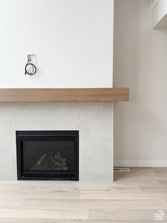 Interior details featuring a fireplace, wood finished floors, visible vents, and baseboards