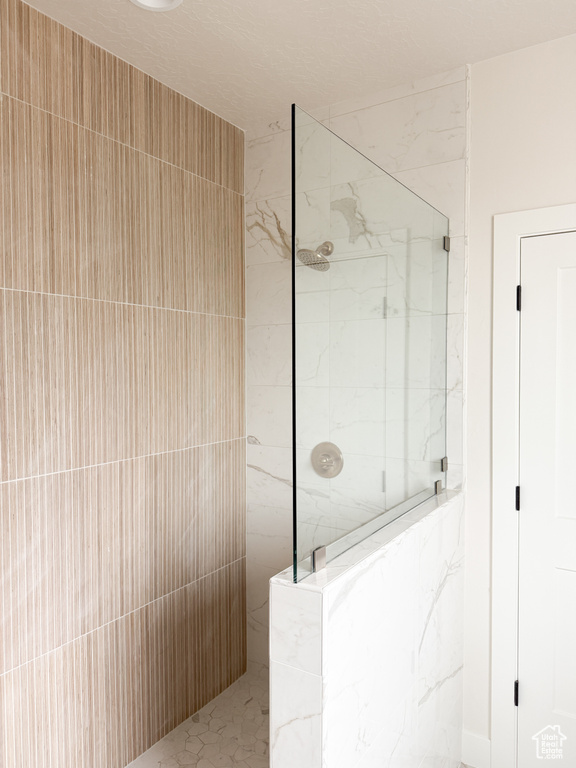 Full bath with a marble finish shower
