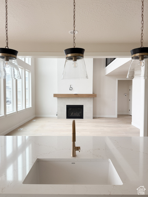 Unfurnished living room featuring a glass covered fireplace, a textured ceiling, a ceiling fan, and a sink
