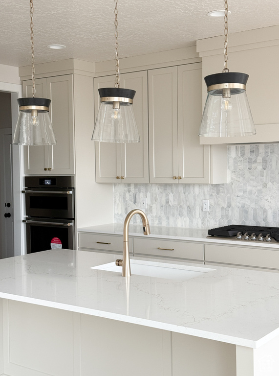 Kitchen featuring stainless steel gas stovetop, a sink, backsplash, and double oven