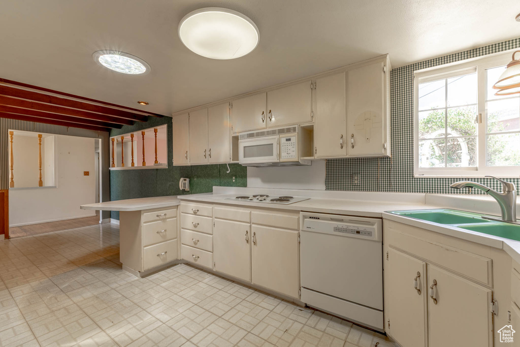 Kitchen featuring decorative backsplash, a sink, light countertops, white appliances, and white cabinetry