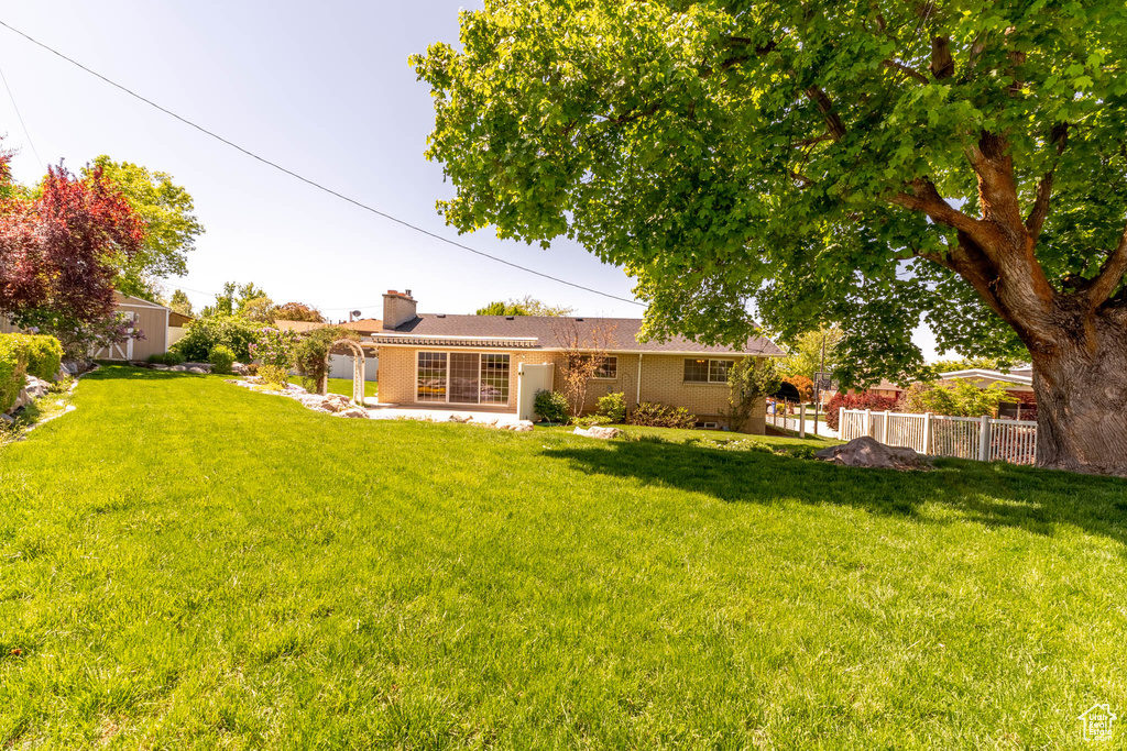 Back of house with fence, a chimney, and a lawn