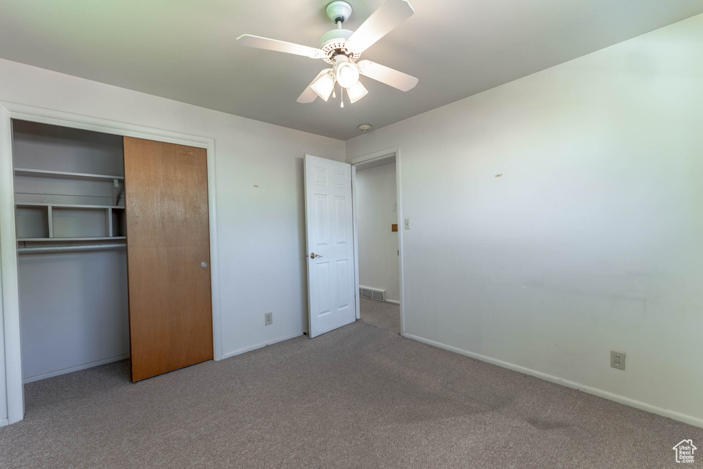 Unfurnished bedroom with carpet, a ceiling fan, baseboards, visible vents, and a closet