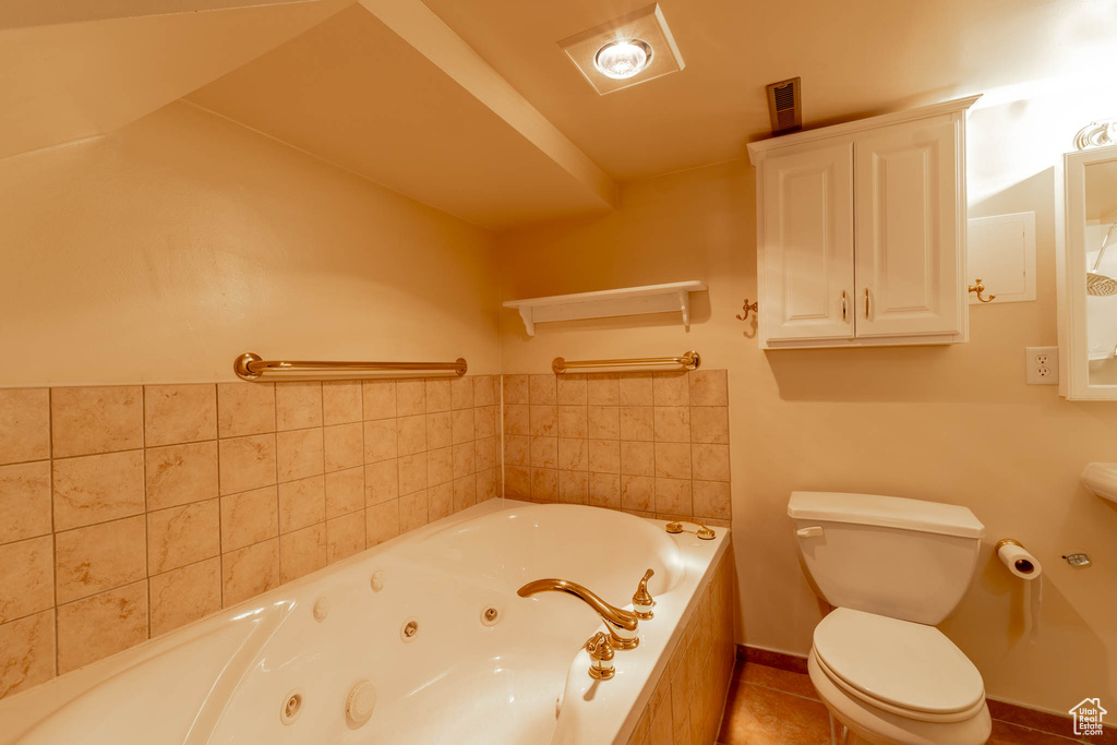 Full bathroom with toilet, tile patterned floors, and a whirlpool tub