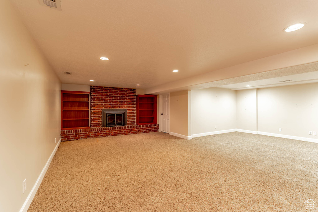 Unfurnished living room featuring carpet floors, baseboards, a brick fireplace, and recessed lighting