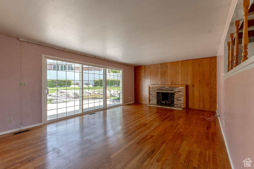 Unfurnished living room with visible vents, baseboards, and wood finished floors