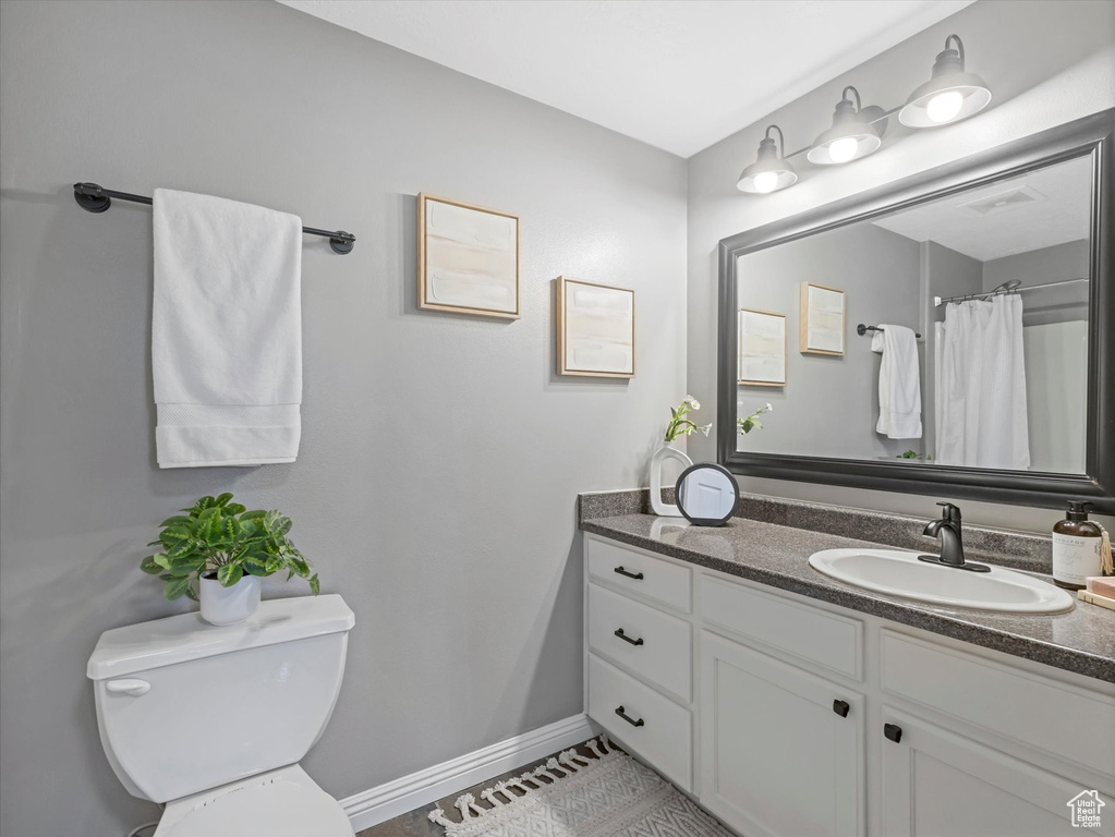 Full bath featuring vanity, baseboards, tile patterned floors, and toilet