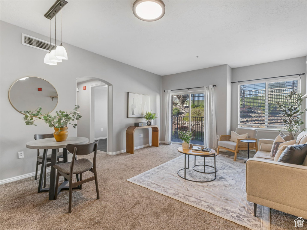 Living room featuring arched walkways, baseboards, carpet flooring, and visible vents