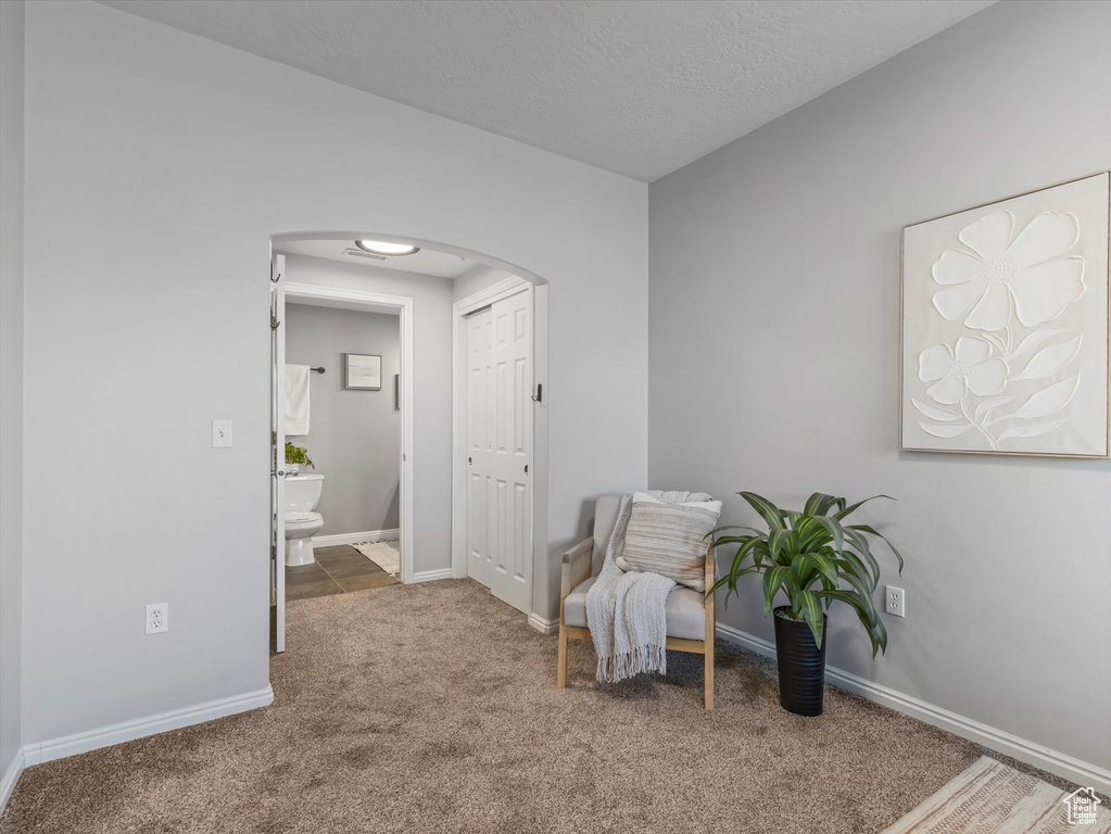 Living area with carpet floors, arched walkways, and baseboards