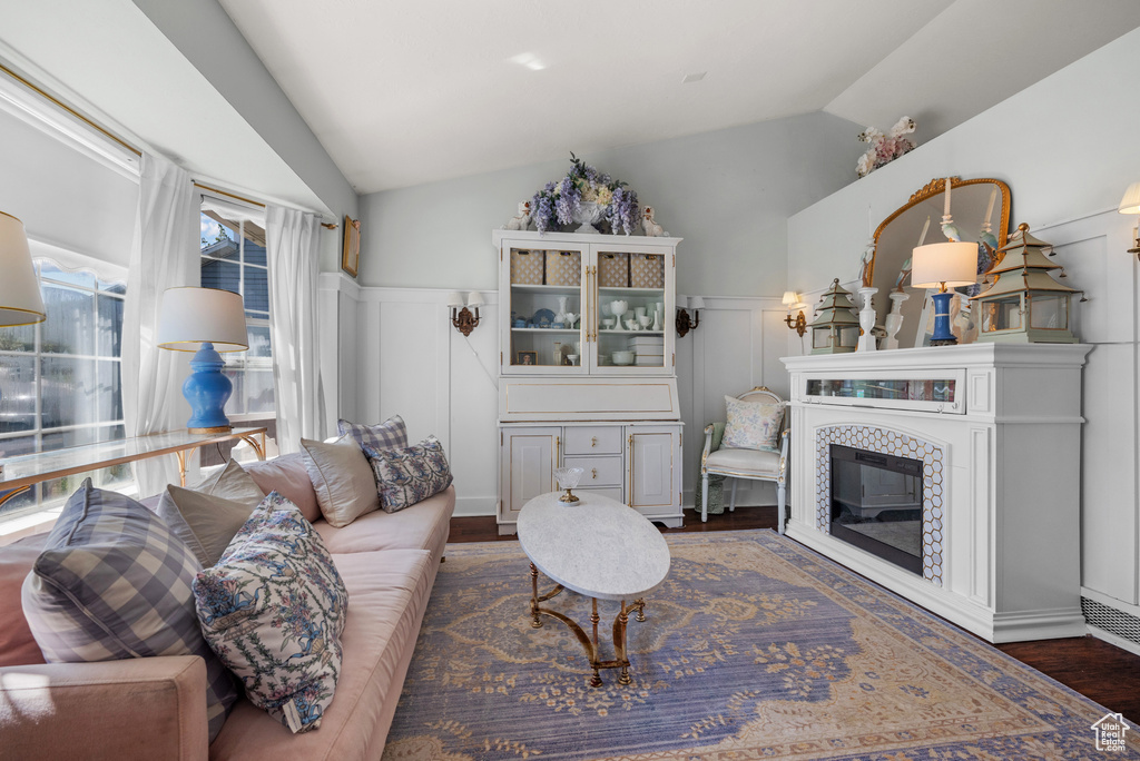 Living room featuring a decorative wall, lofted ceiling, dark wood-style floors, and a wainscoted wall