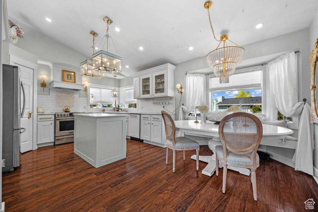 Kitchen featuring appliances with stainless steel finishes, an inviting chandelier, decorative backsplash, and a center island