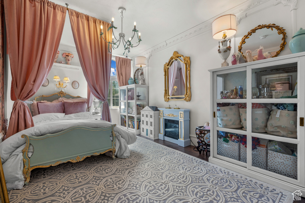 Bedroom featuring an inviting chandelier, a fireplace, and wood finished floors