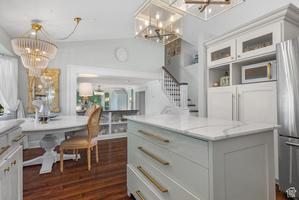 Kitchen featuring an inviting chandelier, freestanding refrigerator, and dark wood-type flooring