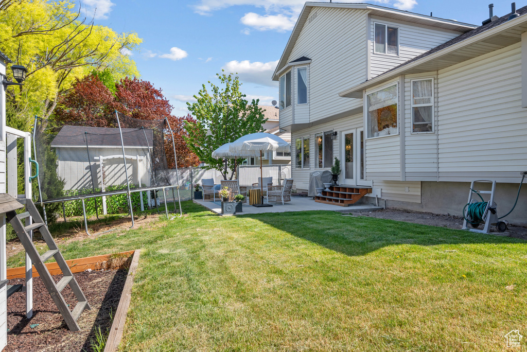 View of yard with fence private yard, a vegetable garden, an outdoor structure, a storage unit, and a patio