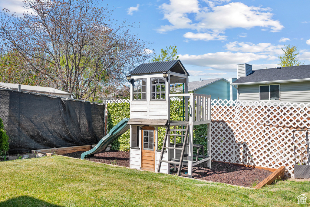 View of jungle gym featuring a lawn, fence, and cooling unit