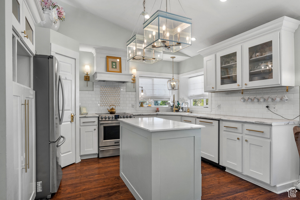 Kitchen with glass insert cabinets, appliances with stainless steel finishes, white cabinets, and tasteful backsplash