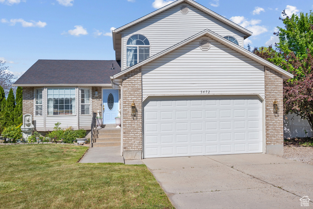 Traditional home featuring brick siding, a garage, a front lawn, and driveway